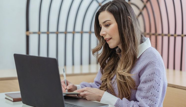كاتبة تدوّن ملاحظاتها أمام اللابتوب لصياغة محتوى قابل للاستخراج